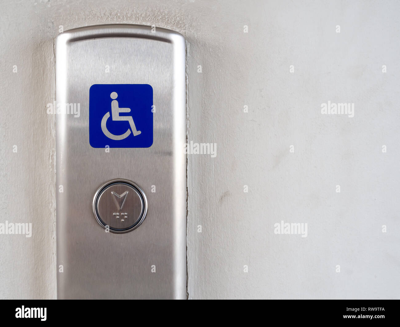 Elevator button with blue disabled people sign on stainless steel elevator panel on old and dirty white background with copy space. Elevator button fo Stock Photo