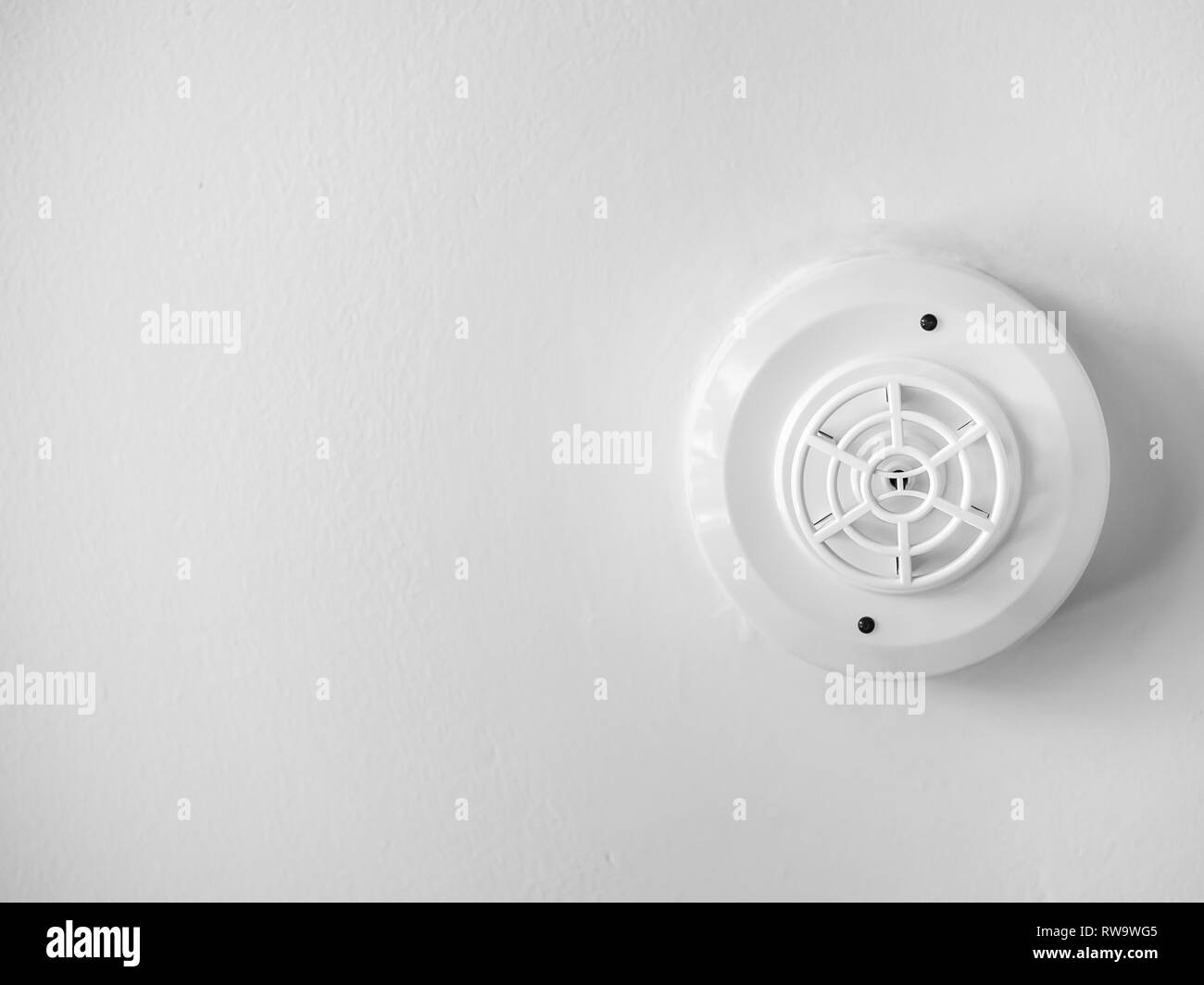 White smoke detector on white ceiling background with copy space. Stock Photo