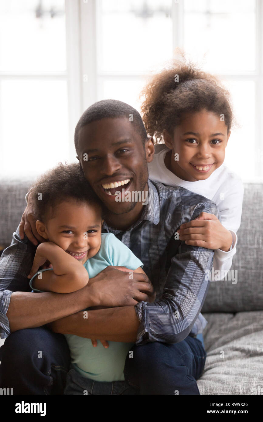 Portrait of happy black dad have fun hugging kids Stock Photo