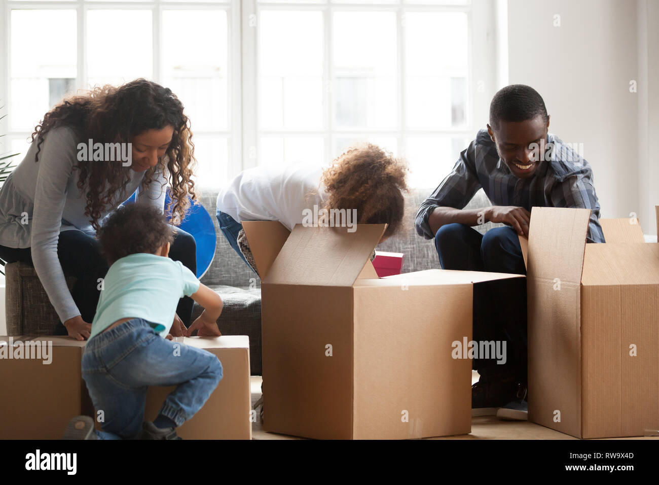 Happy black family with small kids unpack boxes Stock Photo