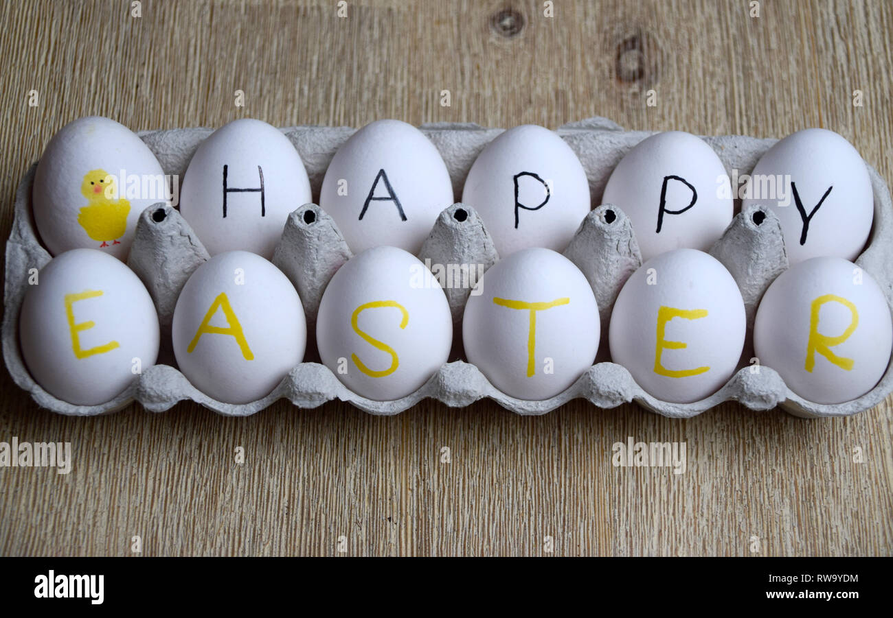 Happy Easter greetings on white eggs in a box on wooden background Stock Photo