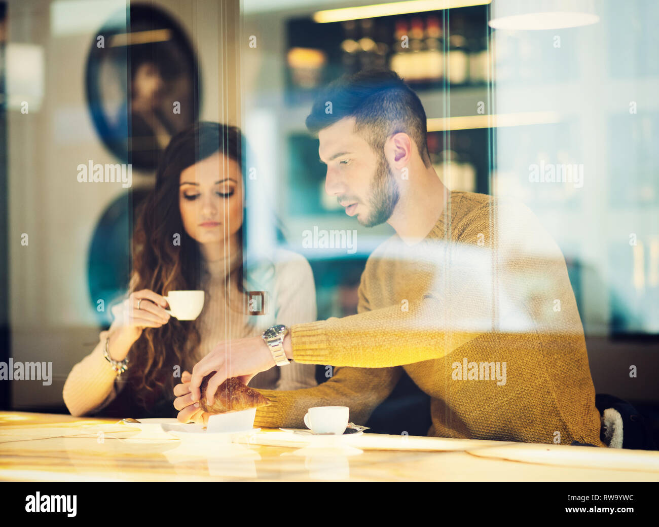 Young couple at the bar drinking an italian espresso. Reflection view from outside. Stock Photo