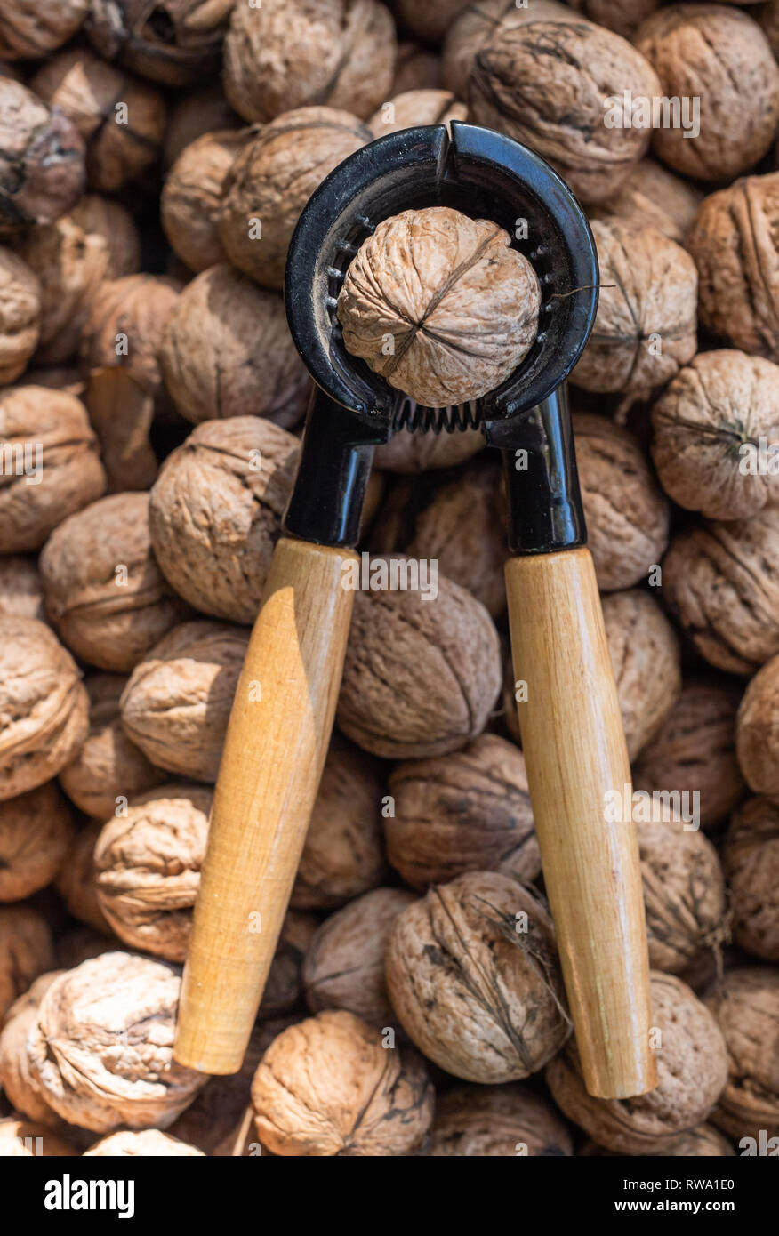 Nutcracker and lot of walnuts on table Stock Photo