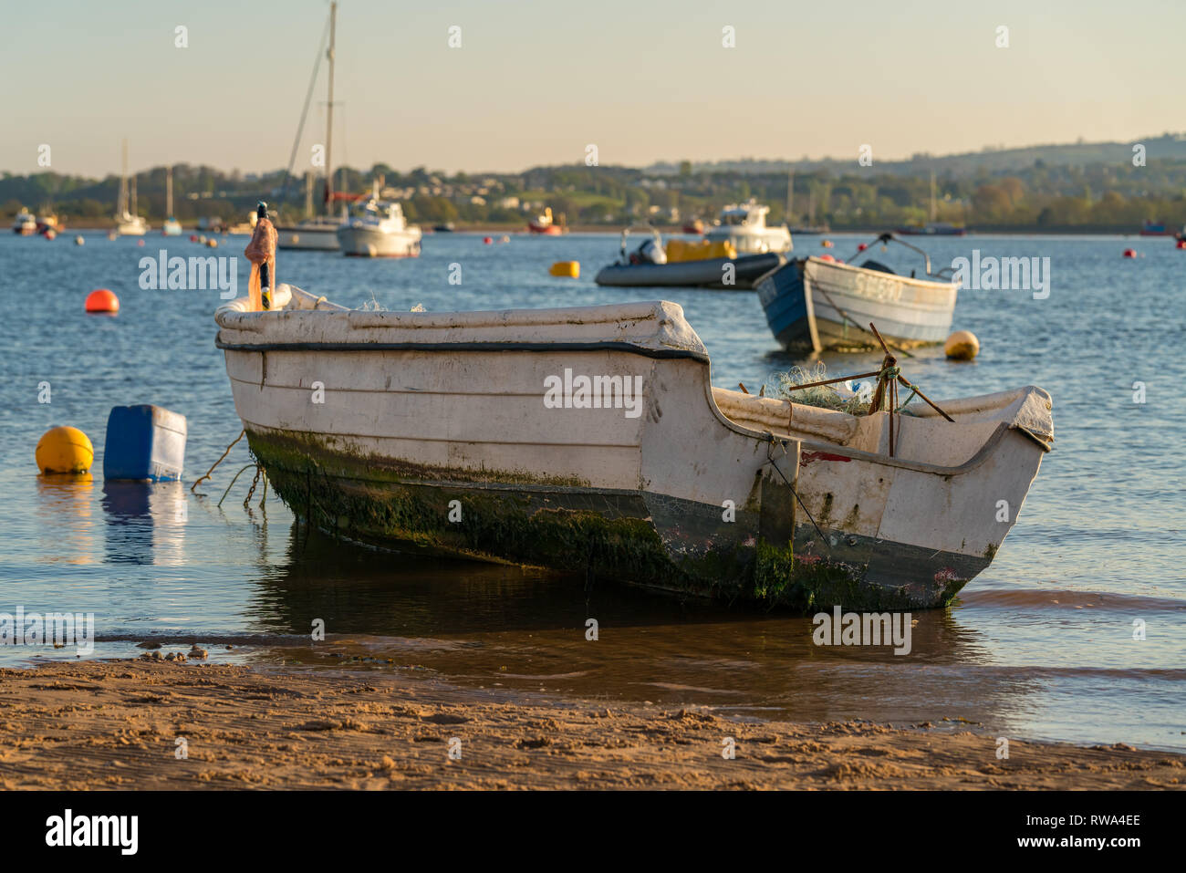 Emouth, Devon, England, UK - April 18, 2017: A Boat on the shore of the River Exe with other boats floating in the river in the background Stock Photo