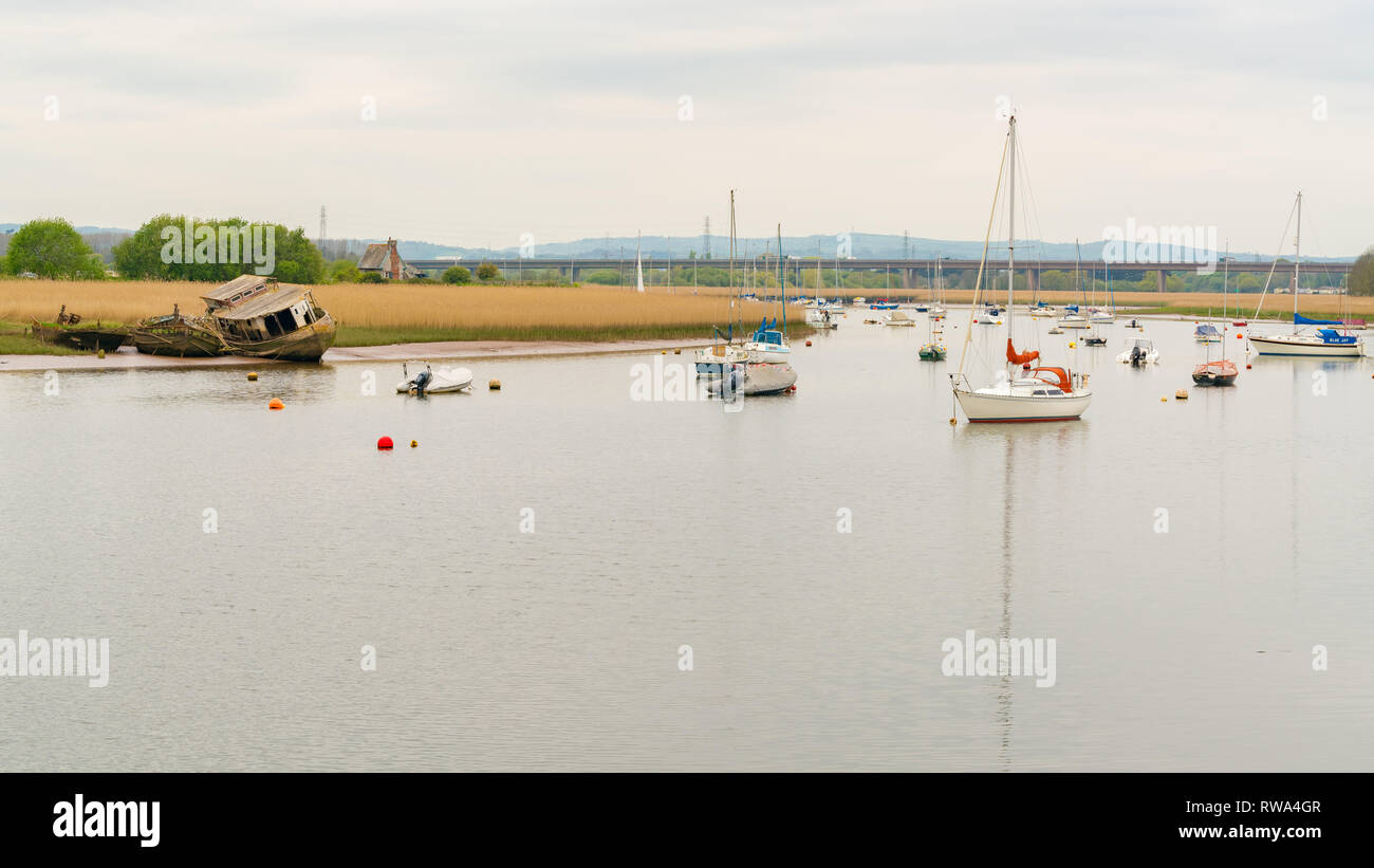 Topsham, Devon, England, UK - April 20, 2017: Shipwrecks at the shore of the Exminster Marshes and some boats on the river Stock Photo