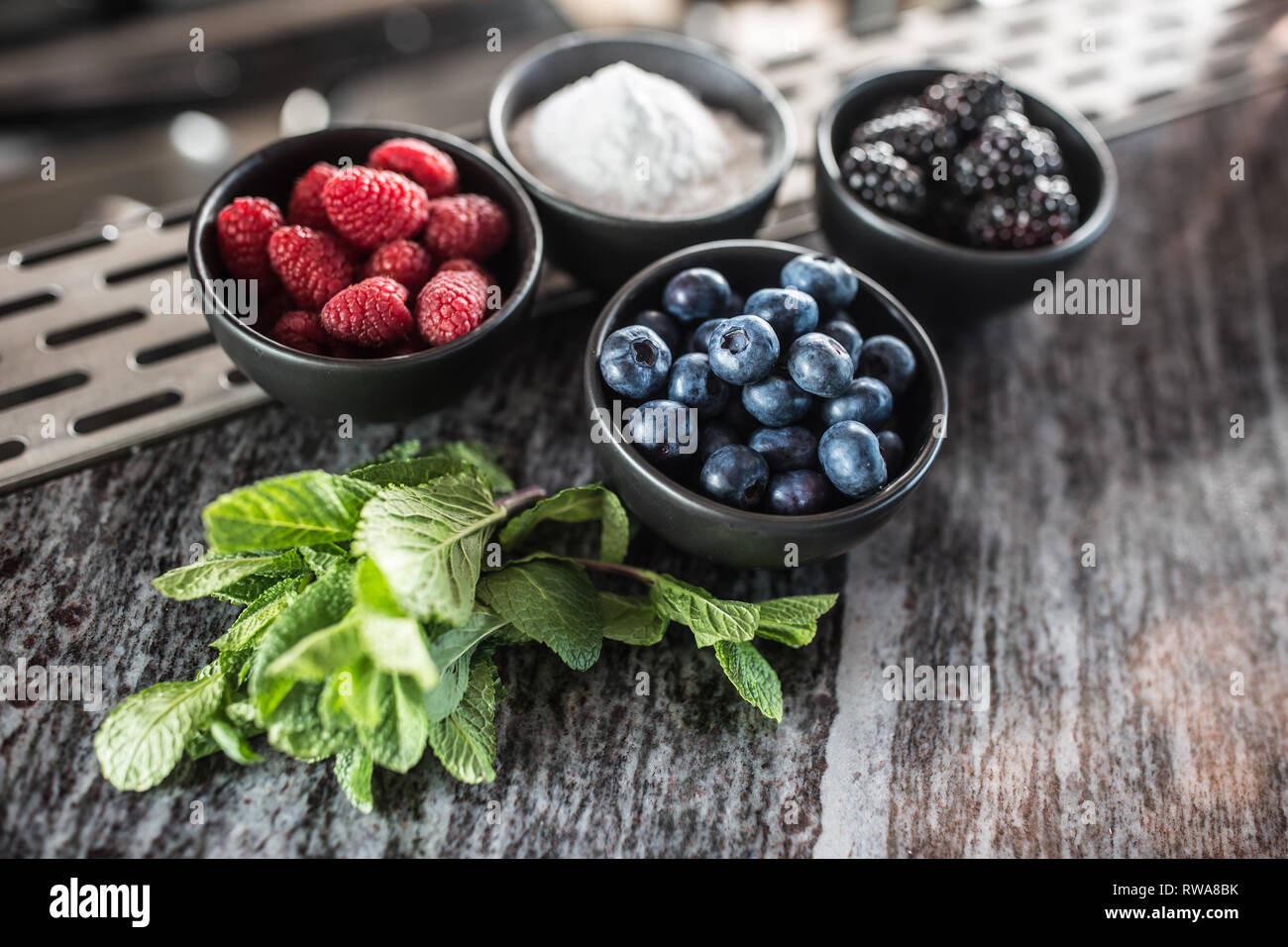 Blueberies raspberries blackberries sugar and mint at barcounter in night club or restaurant. Stock Photo
