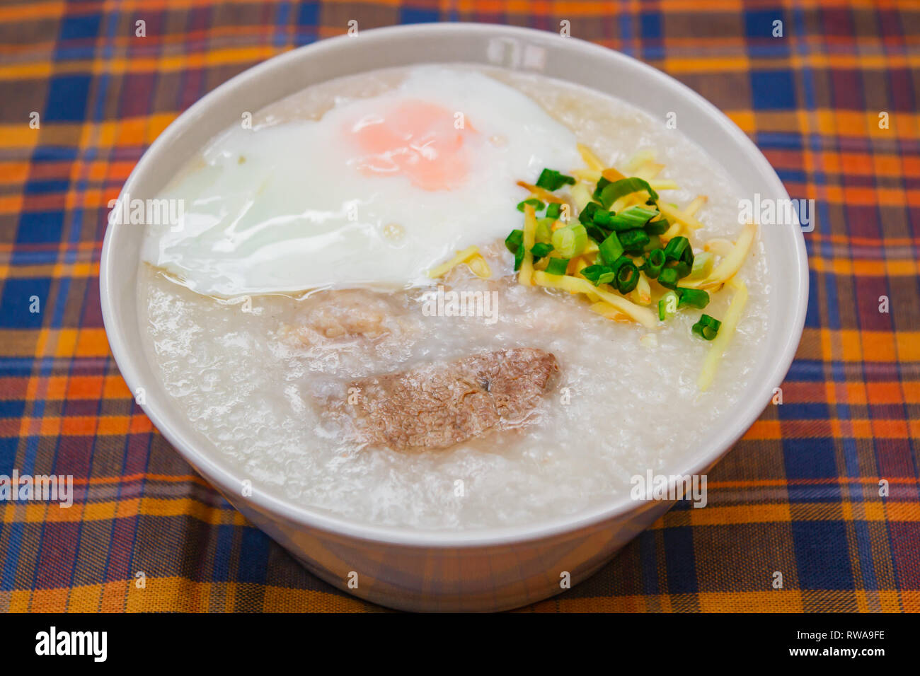 Rice porridge with soft boiled egg, ginger and chopped spring onion