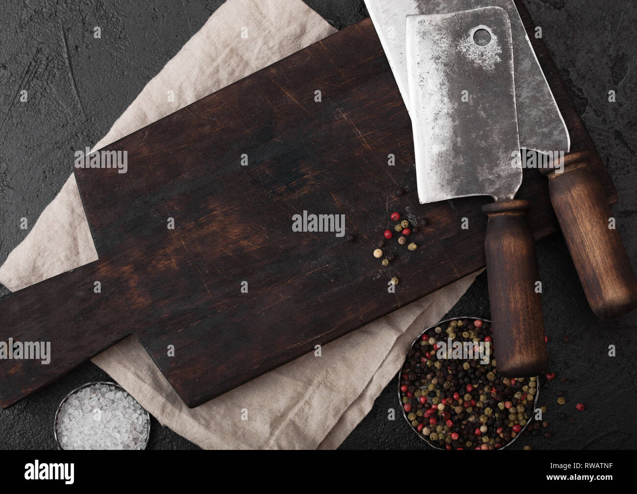 Vintage meat knife hatchet on vintage chopping board and black stone
