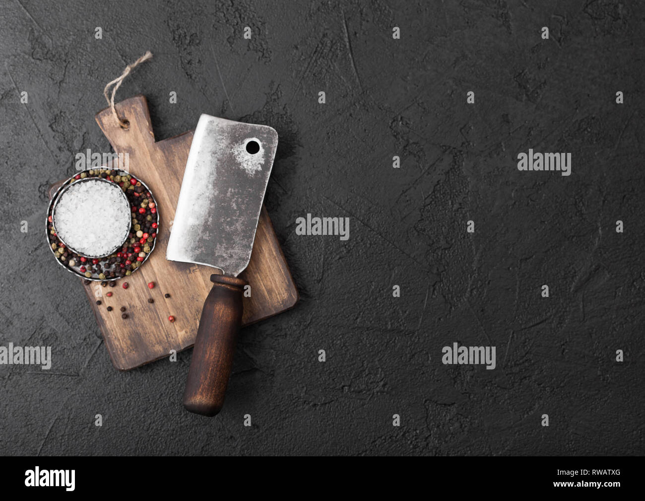 Vintage meat knife hatchet on vintage chopping board and black stone