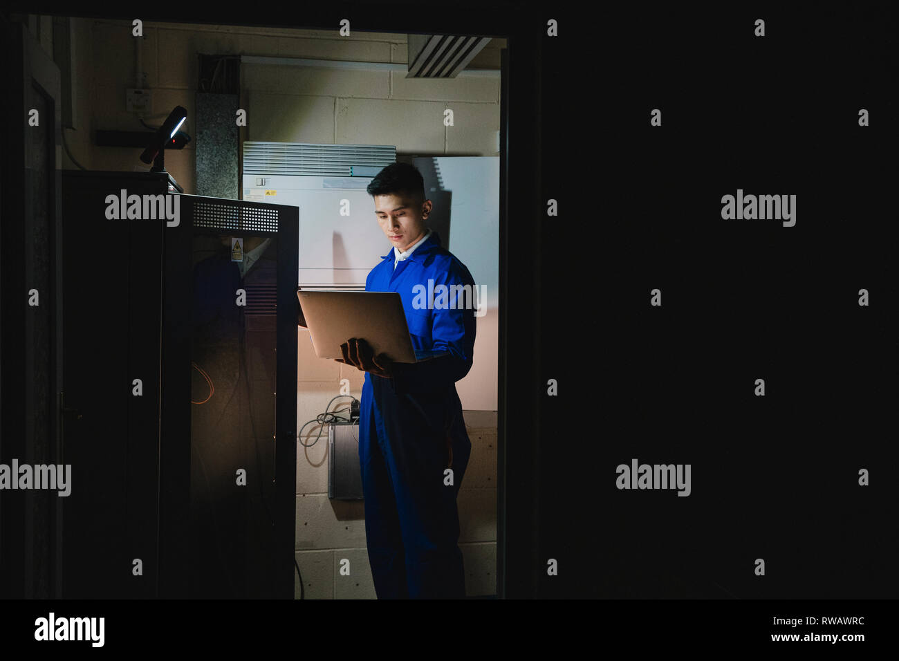 Trainee technician is working in the server room. Stock Photo