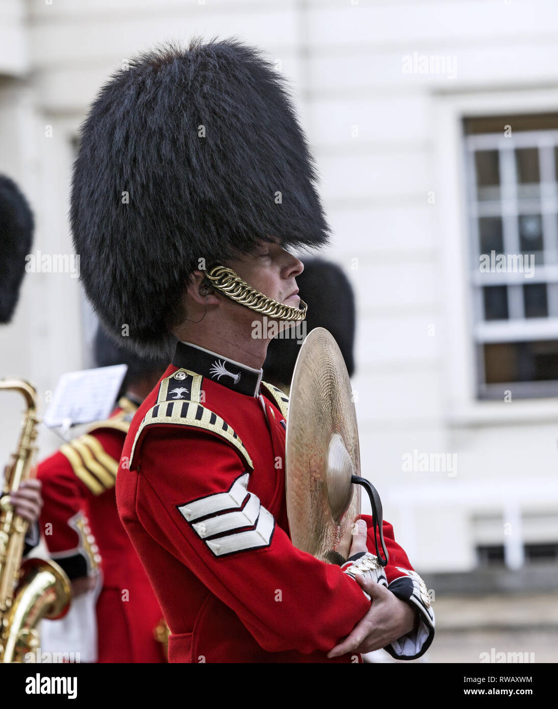 Member of the Band of the Grenadier Guards in London with closed eyes getting ready to play. Wearing bearskin and holding cymbal. Stock Photo