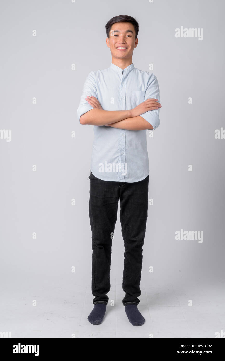 Full body shot of young happy Asian businessman smiling with arms ...