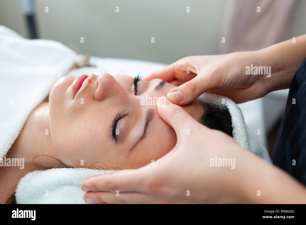 Closeup face of young woman having facial massage at spa. Stock Photo