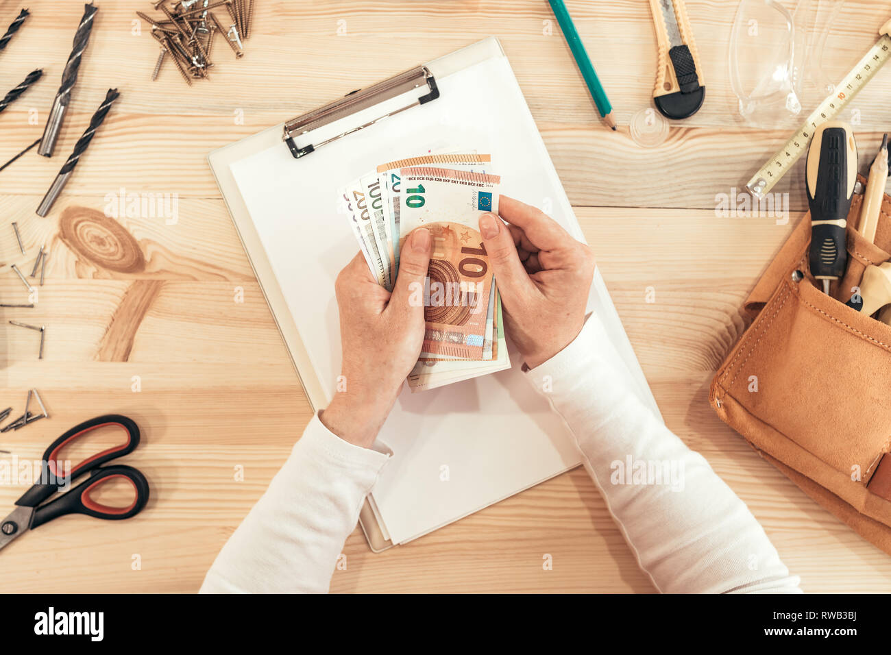 Female carpenter counting money, top view of hands holding European Union Euro paper currency Stock Photo