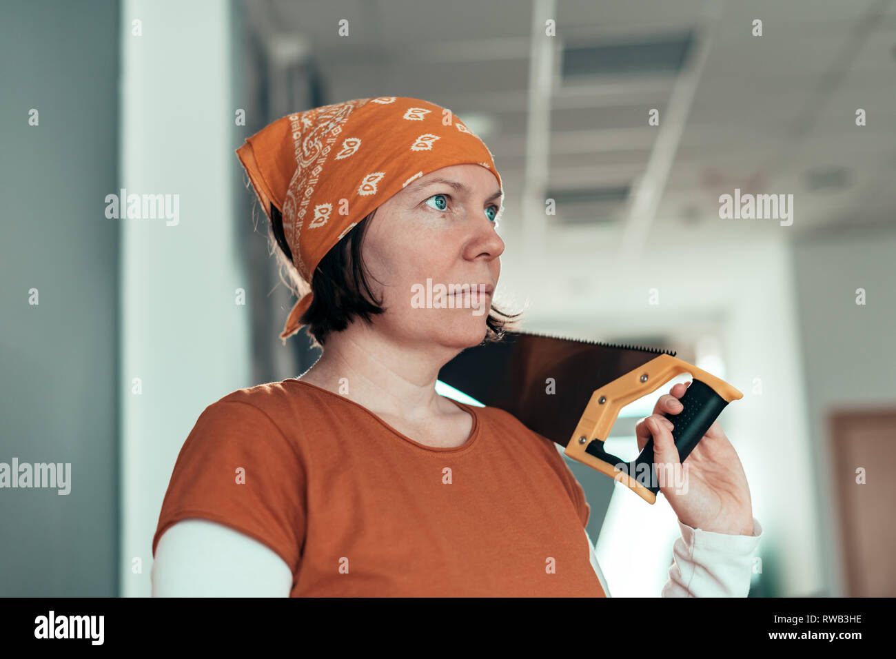 Self employed female carpenter with crosscut hand saw in her small business woodwork workshop Stock Photo