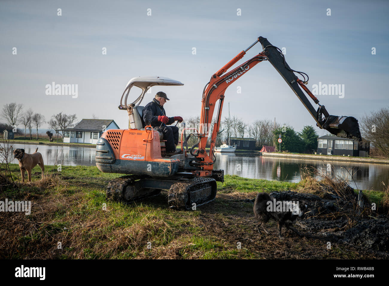 Workman, using a digger and bucket to dredge the River Thurne, on the