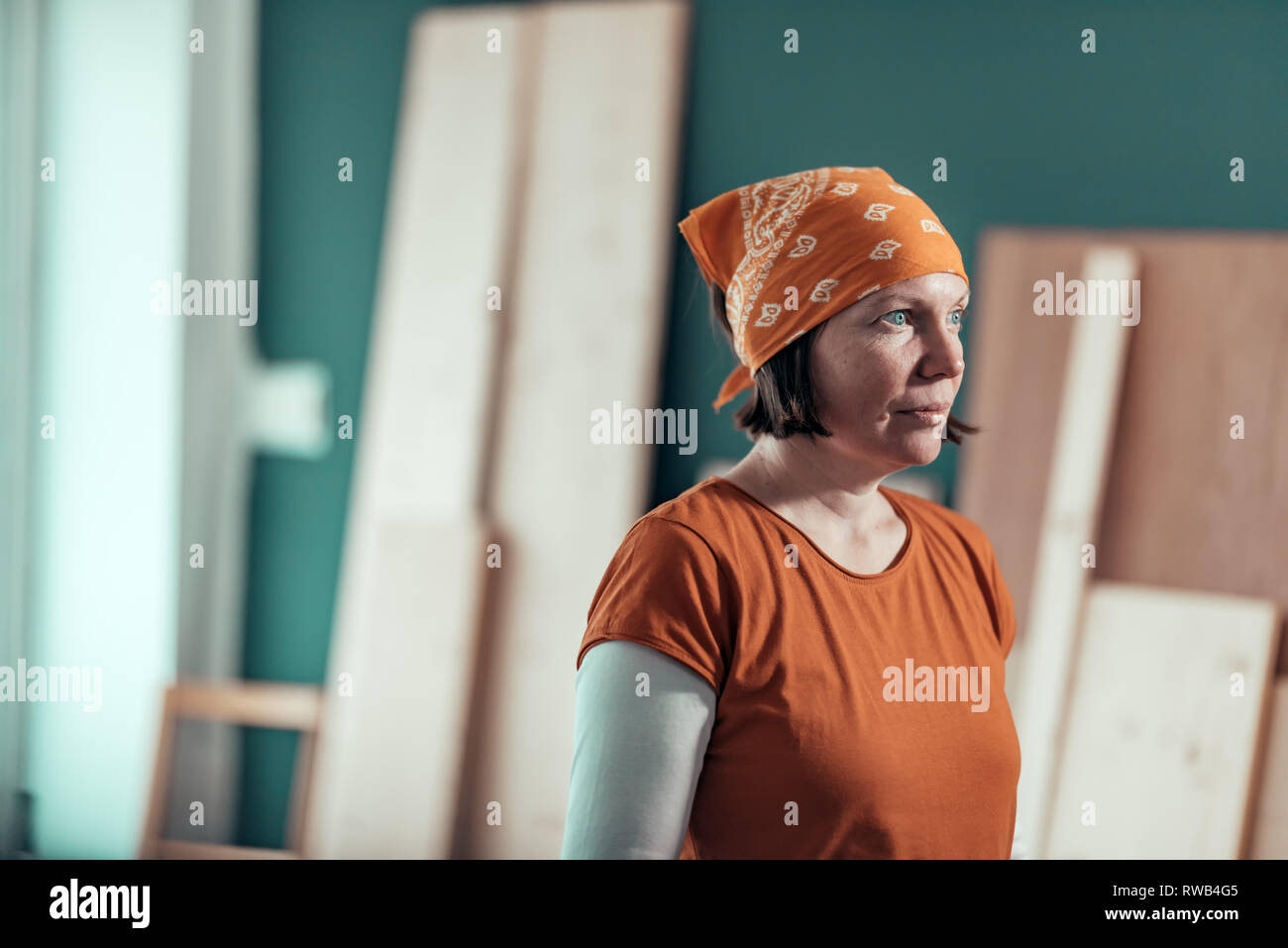 Self employed female carpenter with bandanna posing in woodwork workshop, small business entrepreneur at work place Stock Photo