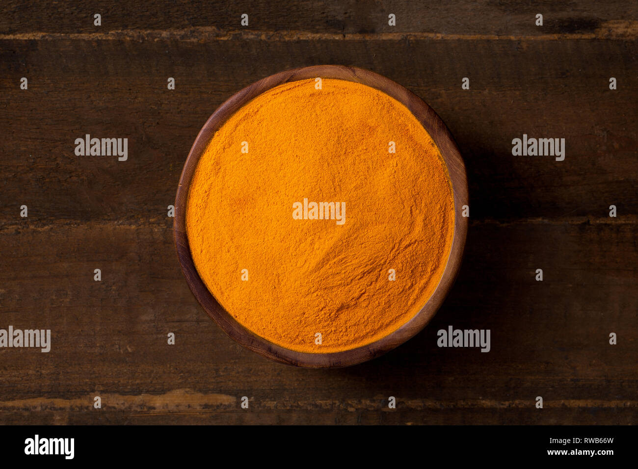 Turmeric curcuma in wooden bowl and wooden background, closeup, top-view Stock Photo