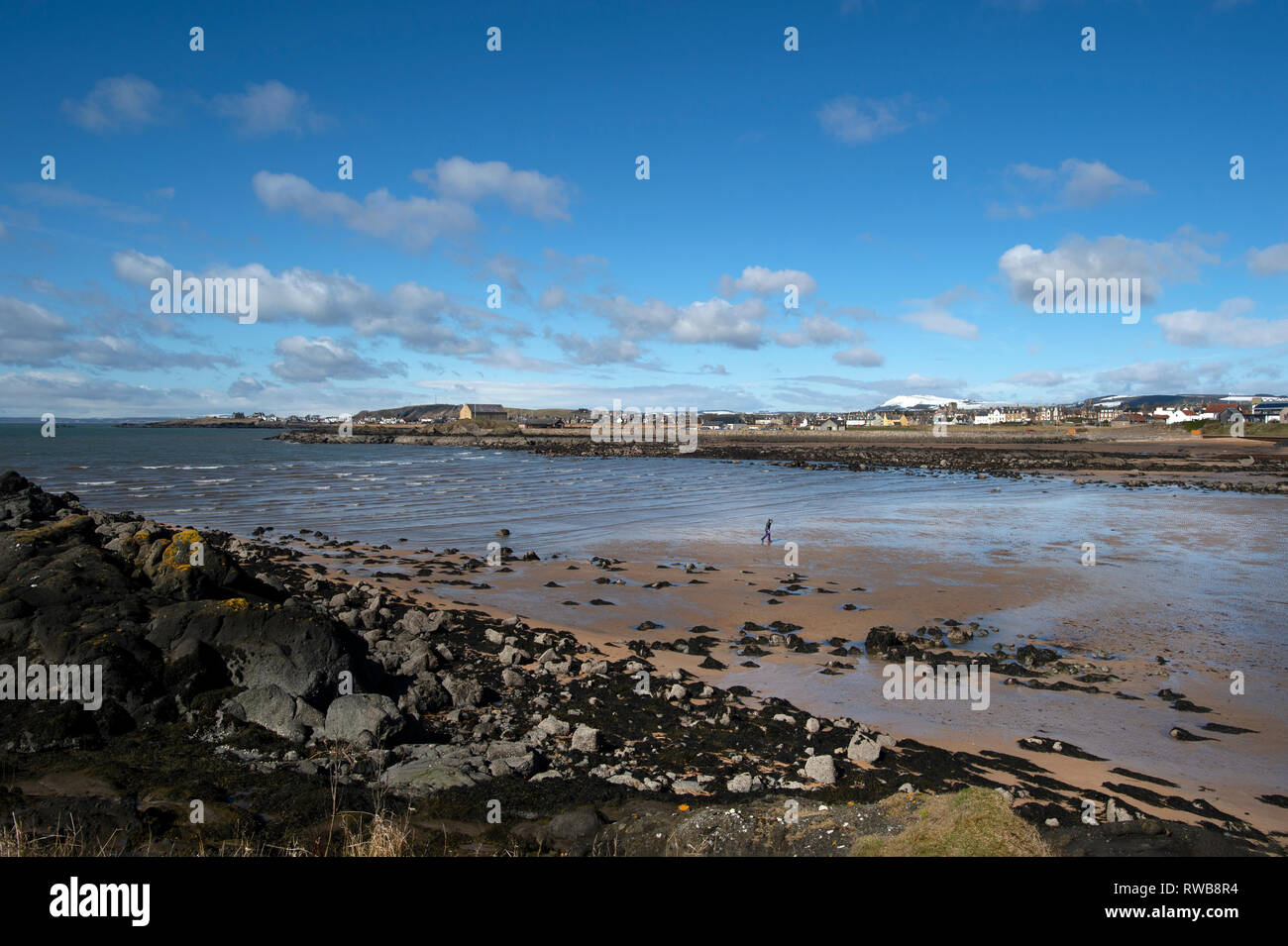 Looking across to the Granary at Elie harbour from Ruby Bay with snowy topped hills in the background Stock Photo