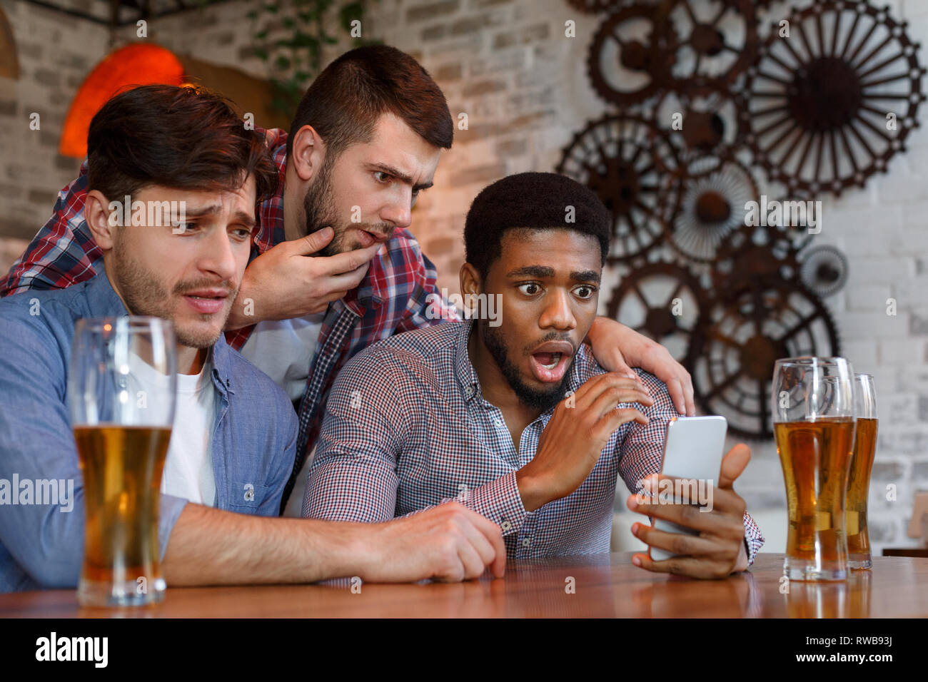 Friends watching football on smartphone in bar Stock Photo
