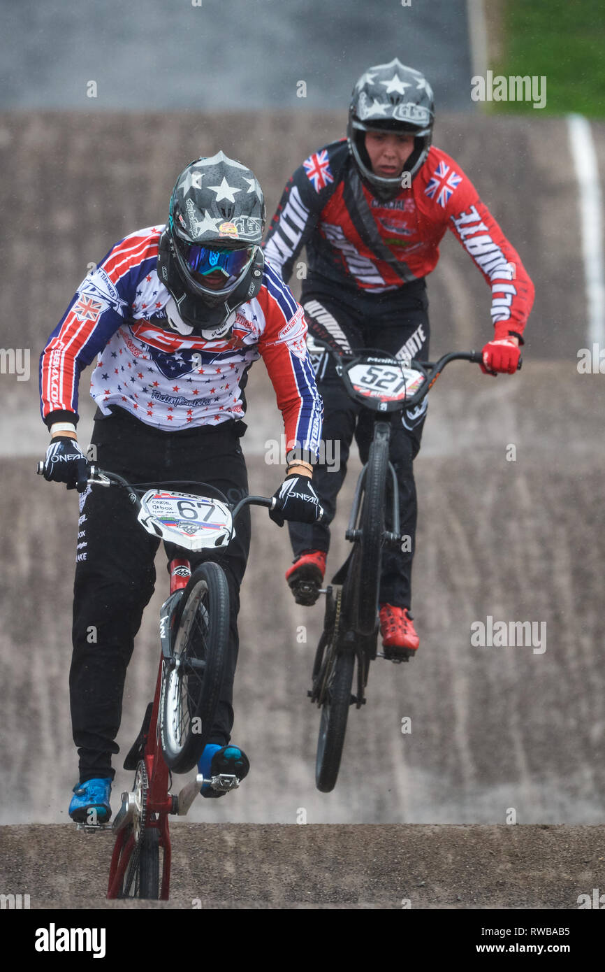 BMX track racing. Rider in mens sprint race event. In difficult conditions from stormy cross winds and heavy rain. Stock Photo