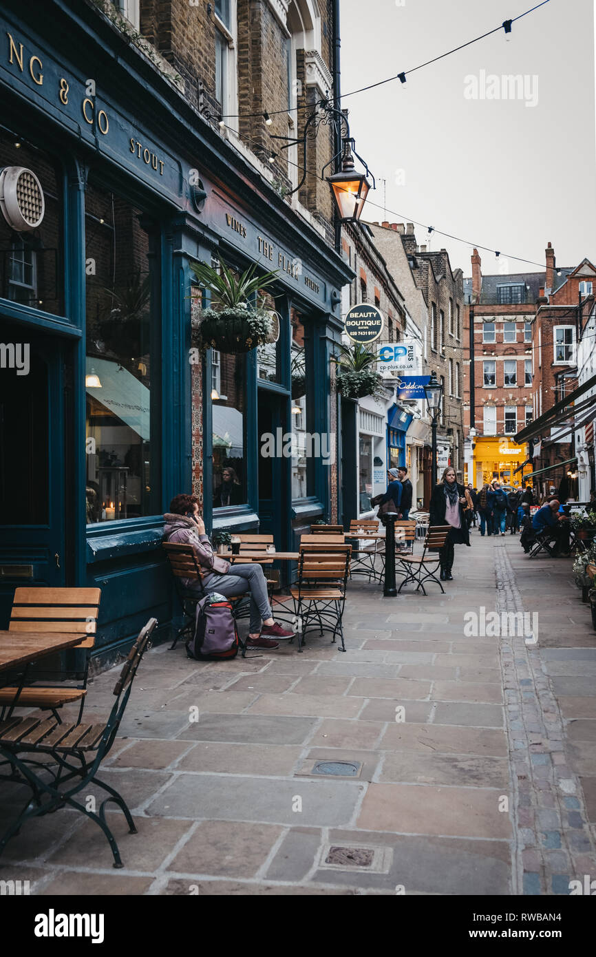 London, UK - March 2, 2019: Woman talking on the phone, sitting at the outdoor table of The Flask pub in Hampstead, an affluent residential area of Lo Stock Photo