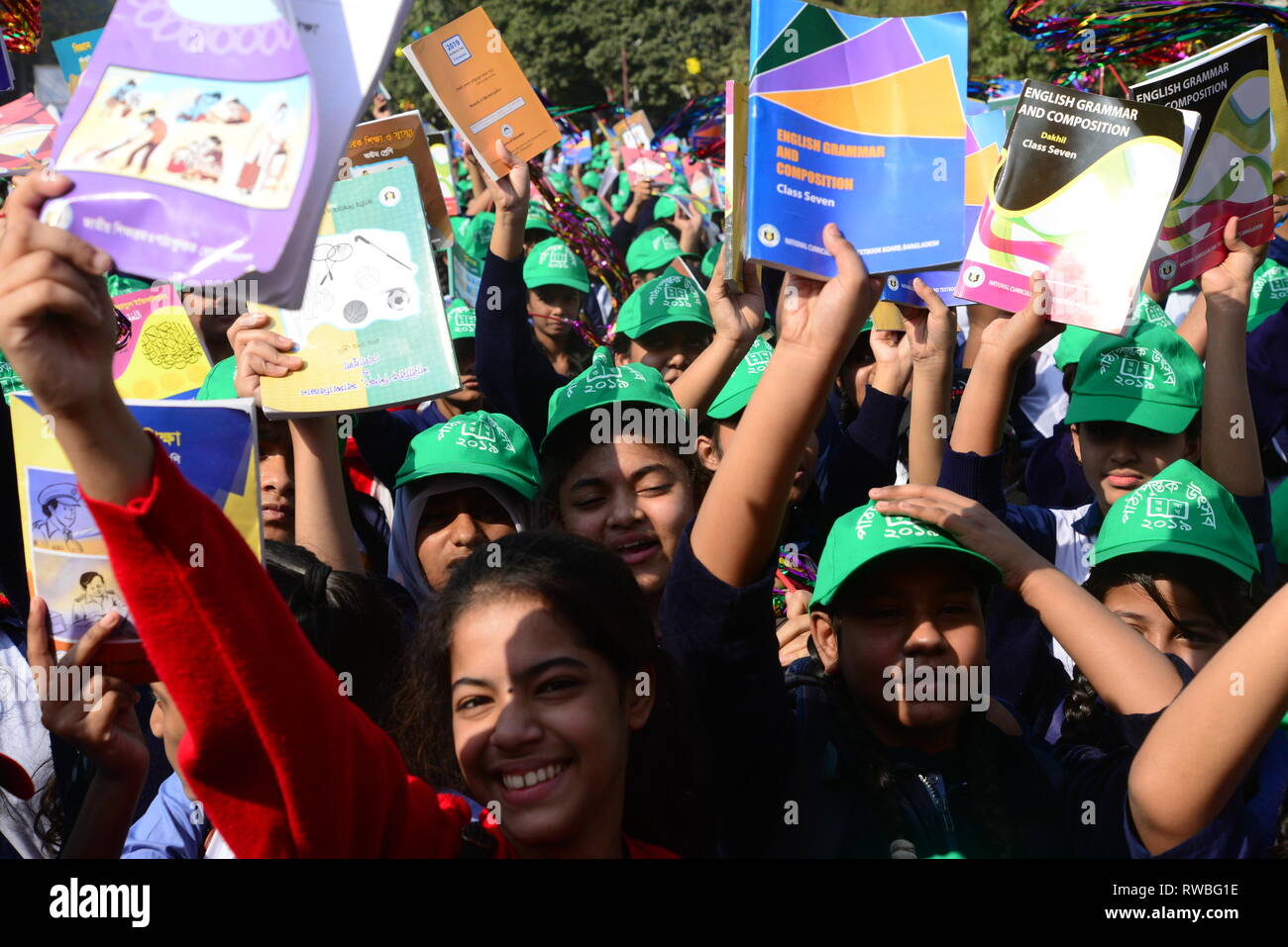 Bangladeshi students raise their books received at a distribution event on 'Textbook Festival Day' in Dhaka, Bangladesh, on January 1, 2019. Students  Stock Photo