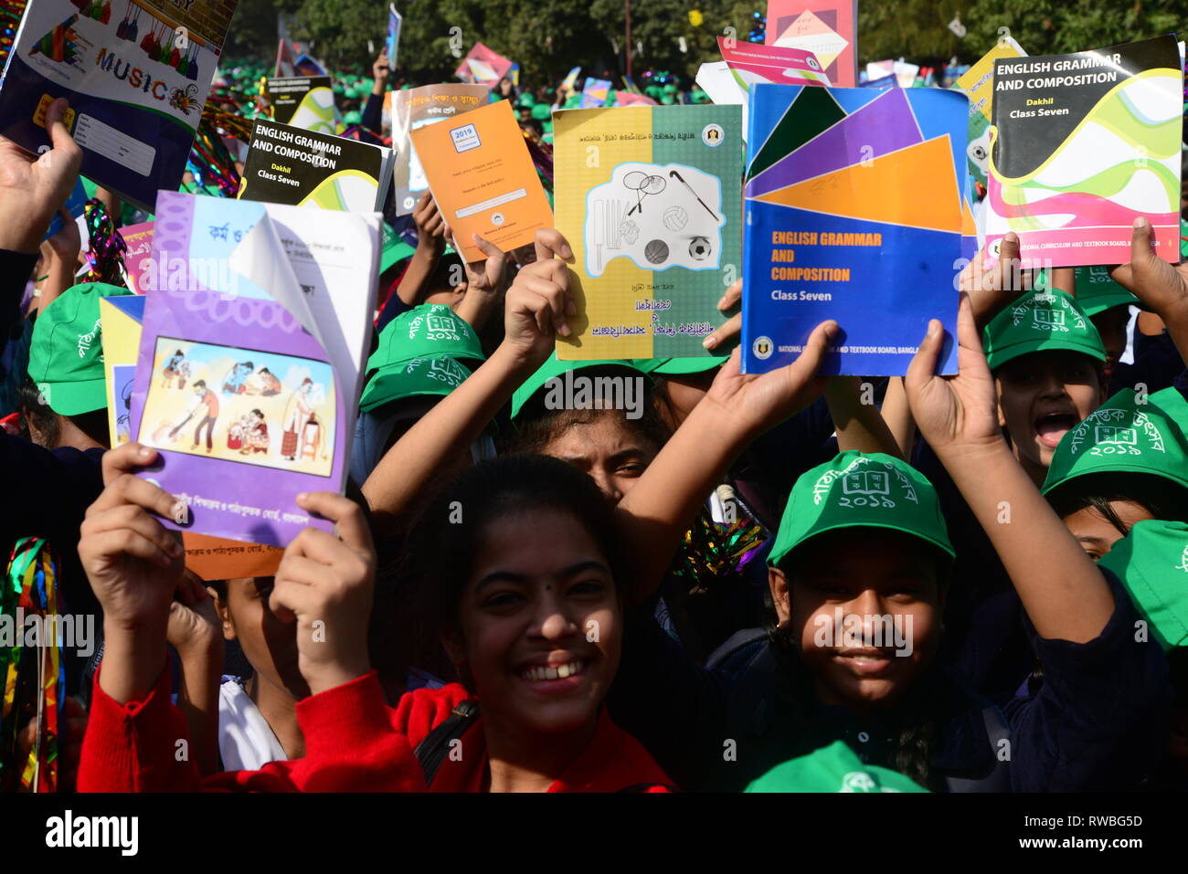 Bangladeshi students raise their books received at a distribution event on 'Textbook Festival Day' in Dhaka, Bangladesh, on January 1, 2019. Students  Stock Photo