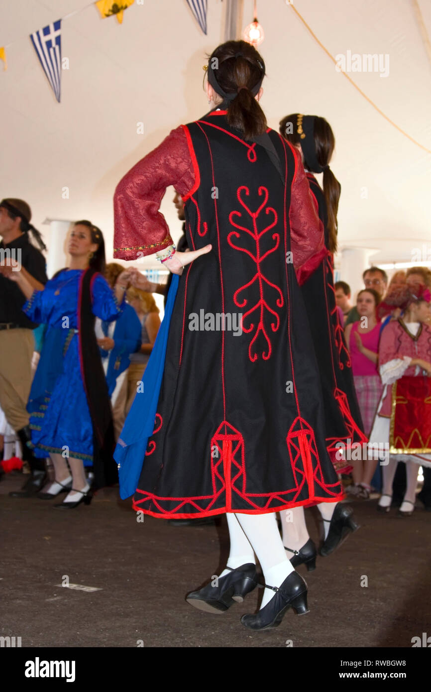 Greek Festival; young women dancing; folk costumes; black, red trim, flags; tent; ethnic celebration, Port Charlotte; FL; Florida; vertical Stock Photo