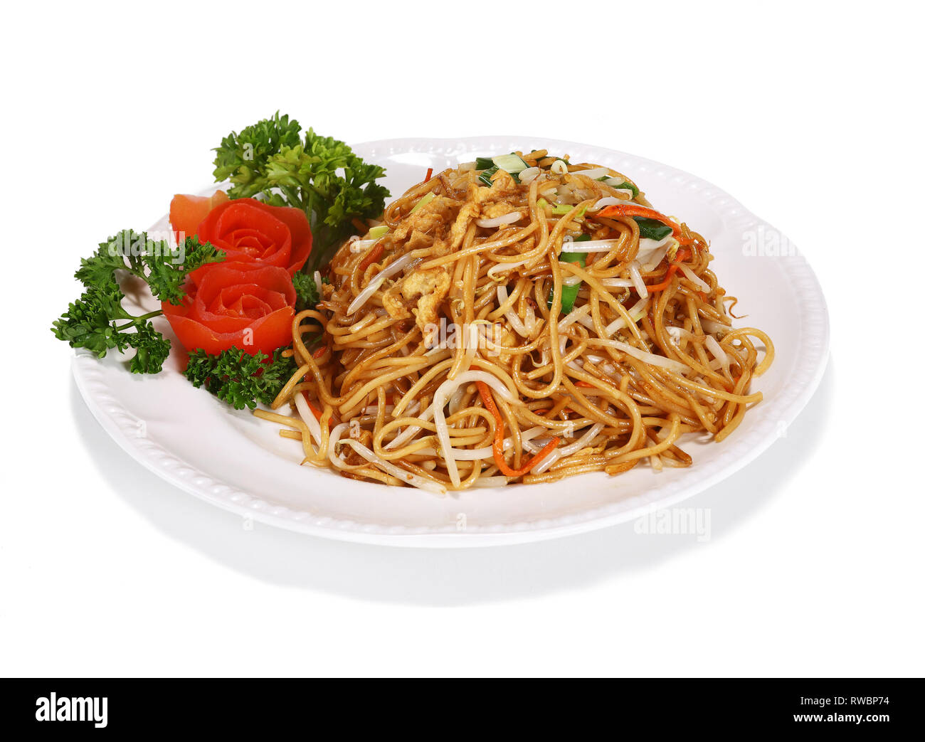 Fried noodles - a typical Asian/Chinese dish. Served on a white plate, garnished with tomatoes and salad. Stock Photo