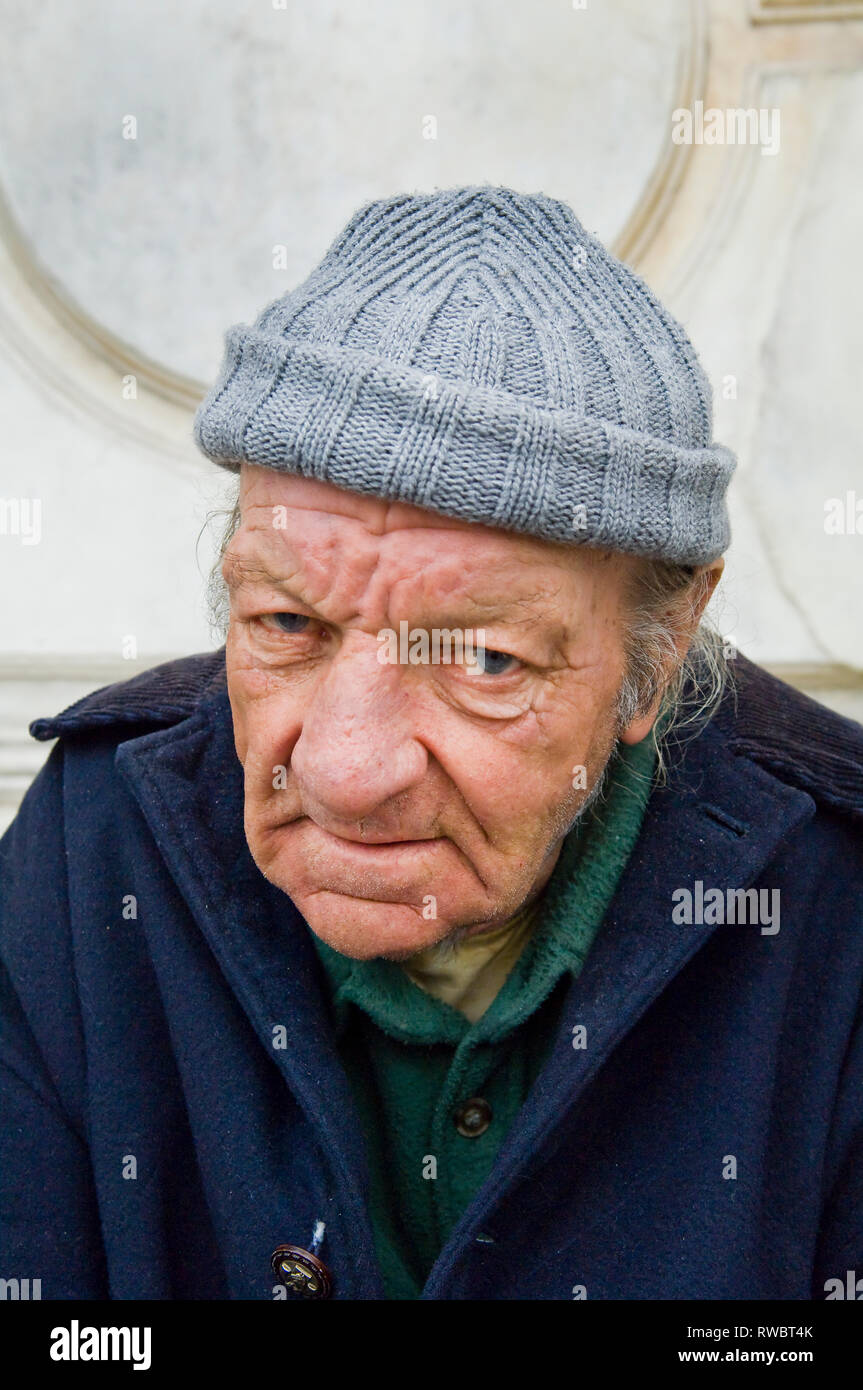 An old man in a grey bobble hat looking at the camera in Venice Stock Photo