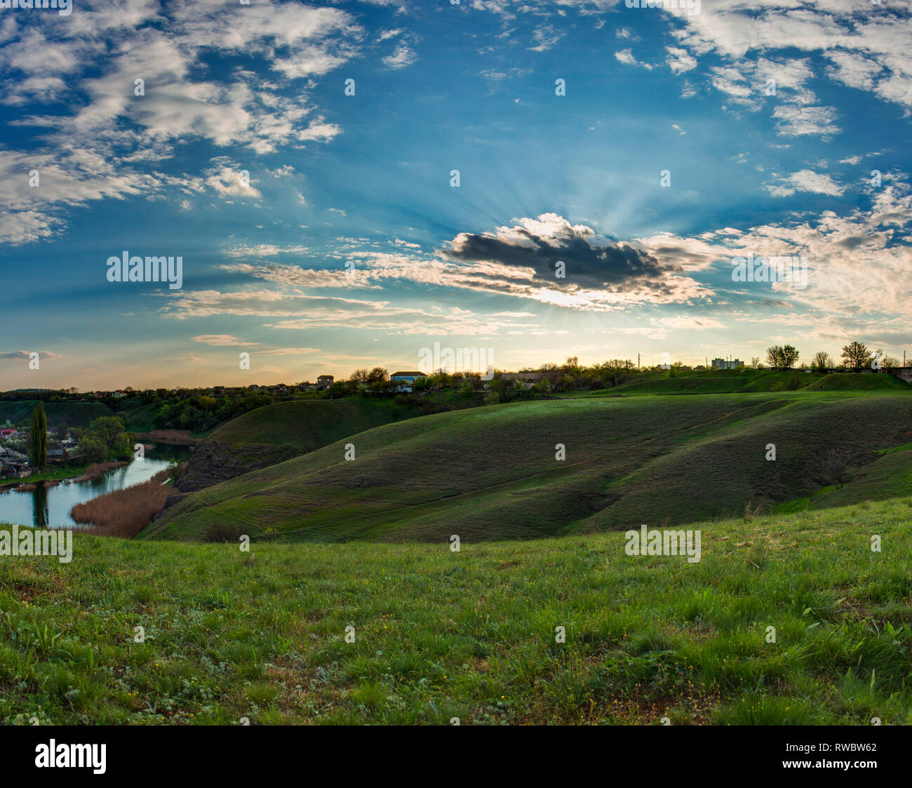 Spring HDR landscape. Ukrainian crags. A hills covered by the green grass. Cloudy sky. Ukraine, Krivoy Rog, MOPR. Stock Photo