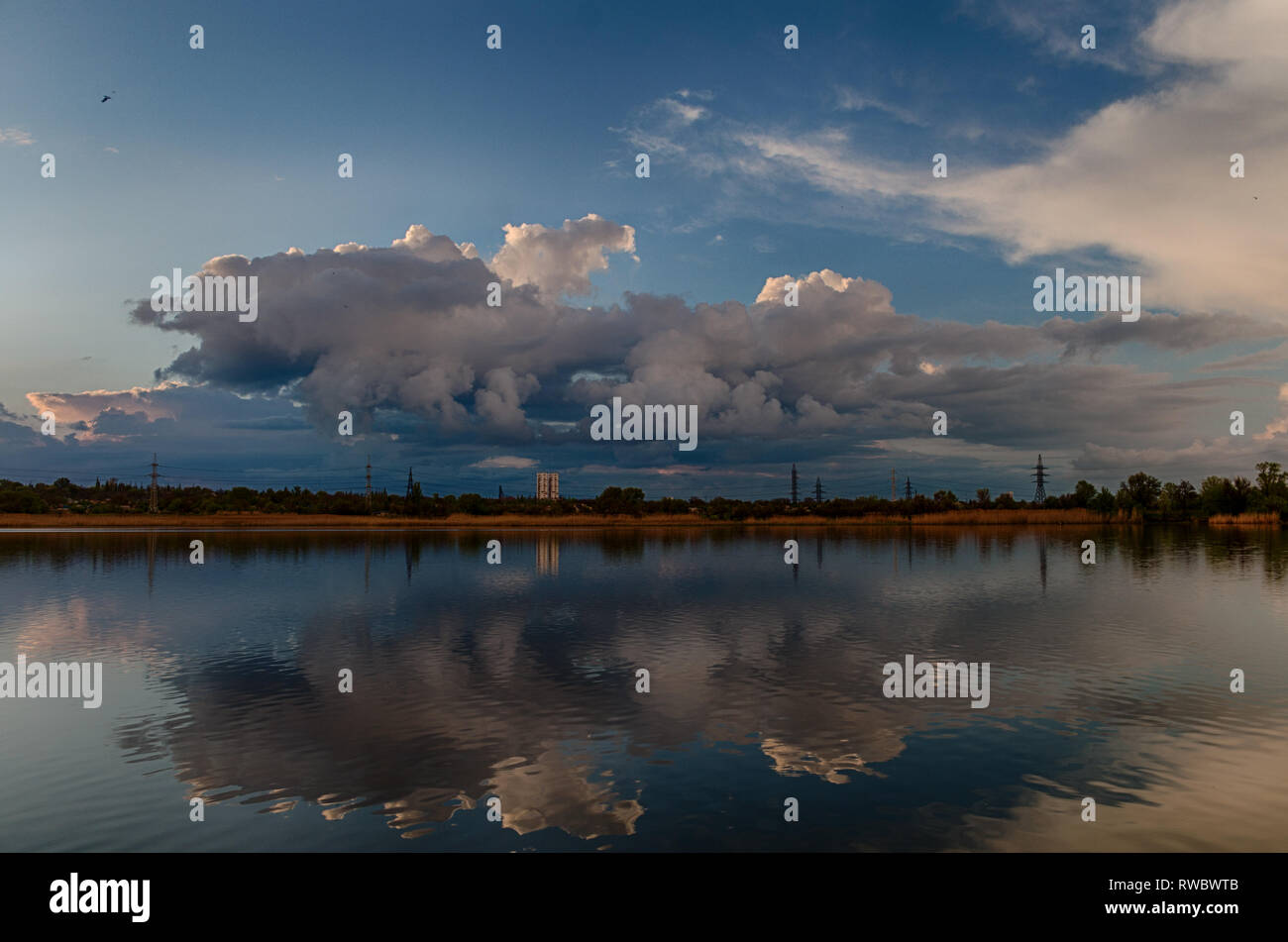 Spring cloudy river landscape with heavy thunderstorm clouds reflected in still water in Ukraine Stock Photo