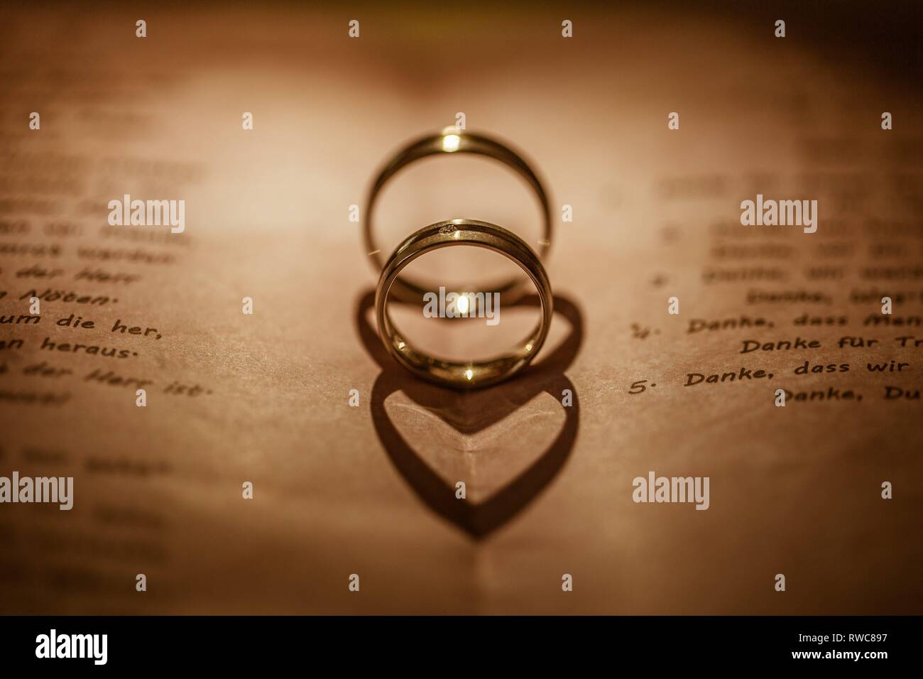 Deutschland. 28th July, 2018. Detail of two wedding rings in a folded lyrics card. The shadow of the rings is heart shaped by the kink in the map. | usage worldwide Credit: dpa/Alamy Live News Stock Photo