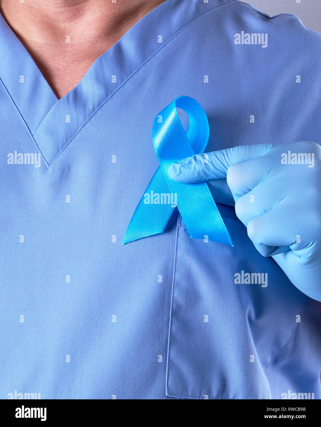 doctor in blue uniform and latex gloves holding a blue ribbon in his hand, a symbol of the fight