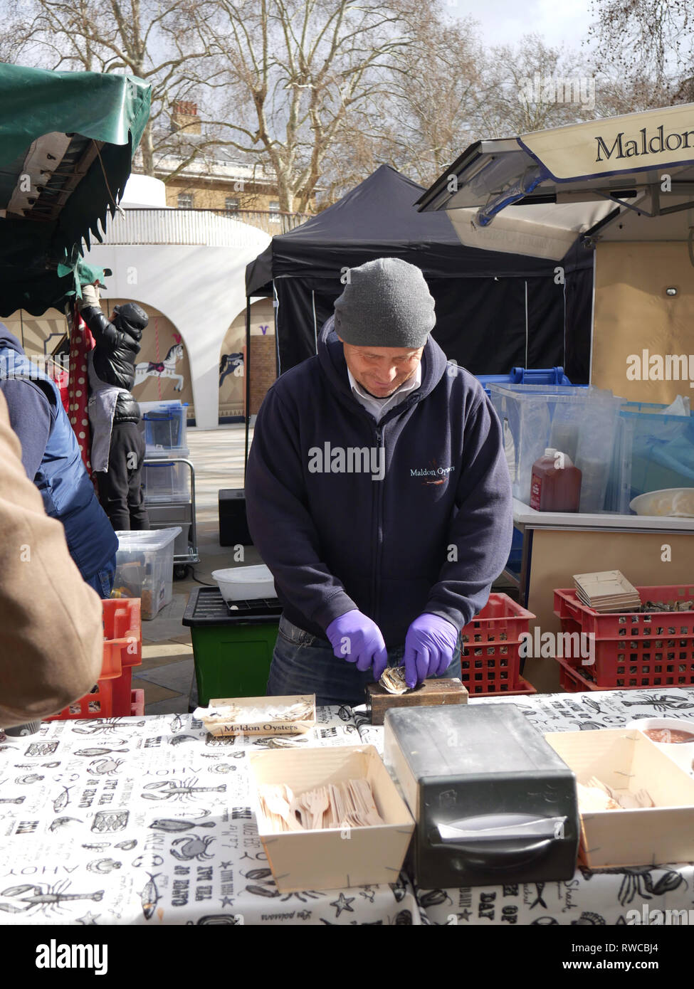 Man opening oysters in Saturday market in Duke of York Square, Chelsea Stock Photo