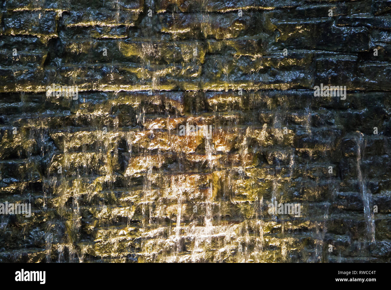 Closeup of dramatically lit stone water fountain with dripping water. Stock Photo