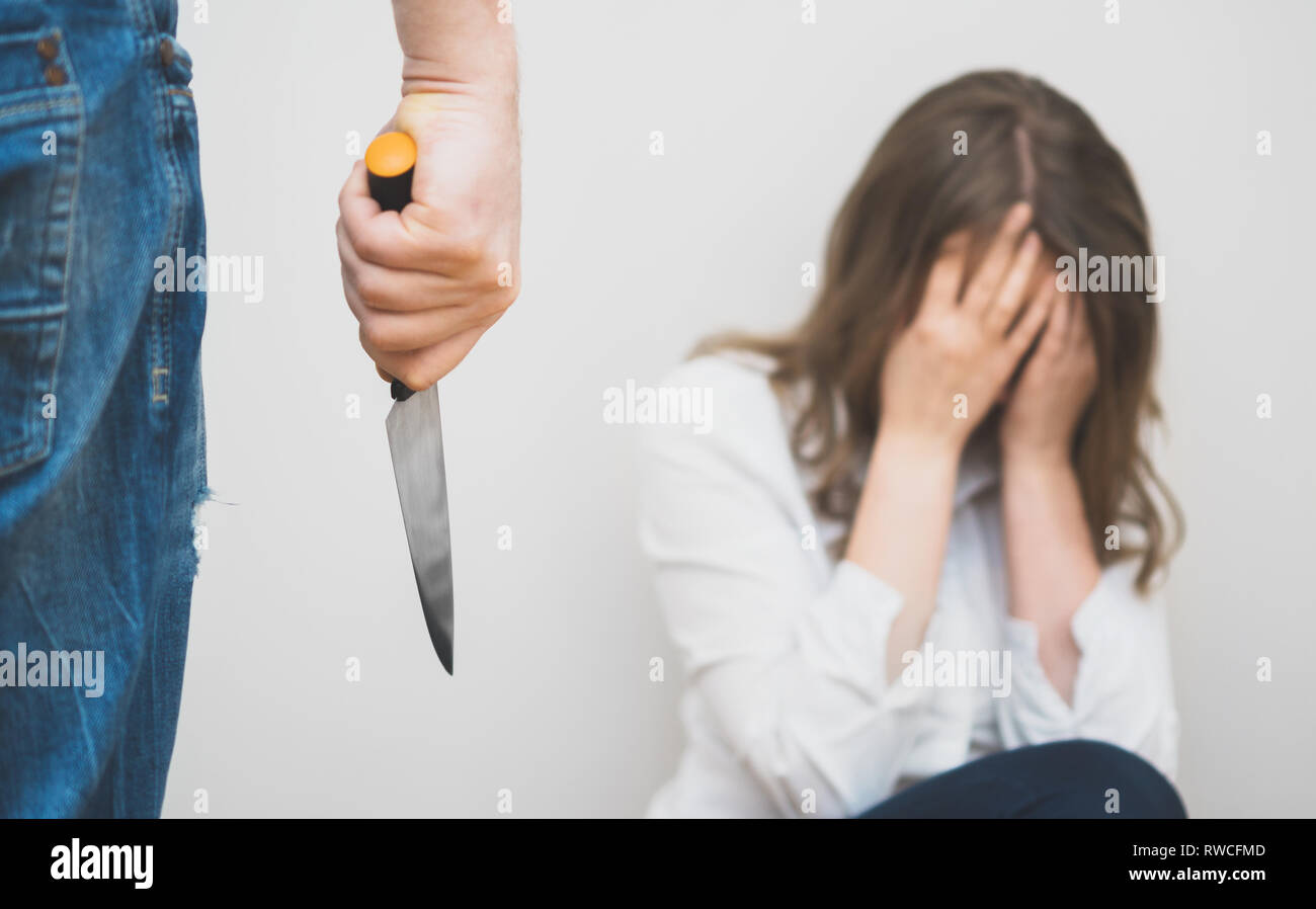 Man with knife coming to his wife. Home violence concept Stock Photo