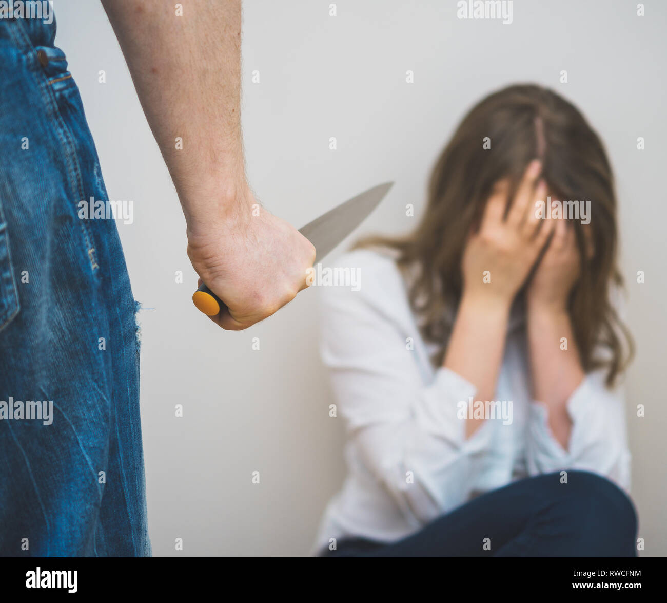 Man with knife coming to his wife. Home violence concept. Stock Photo