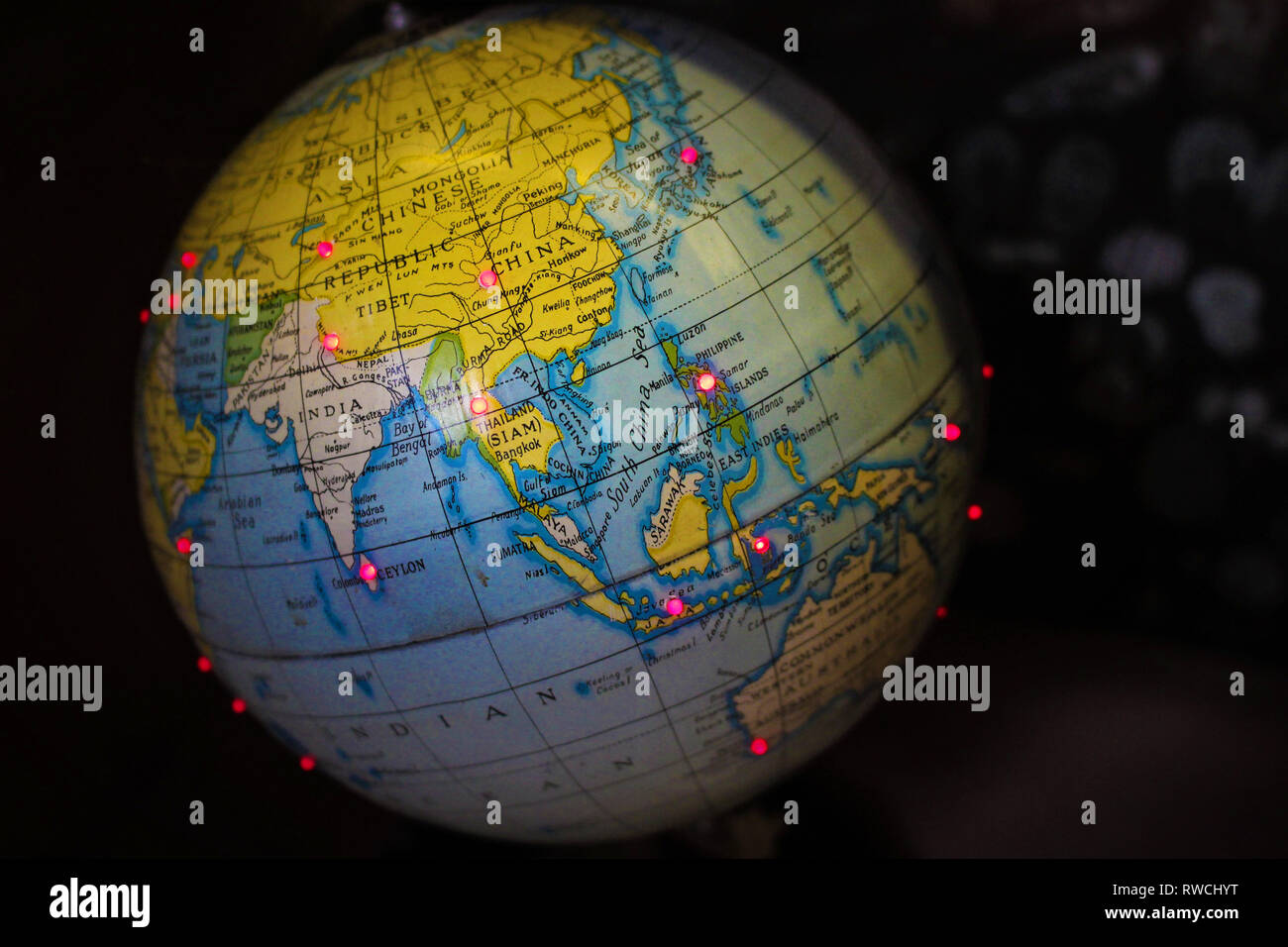 A small world globe map with red LED lights showing China, Thailand, India Stock Photo