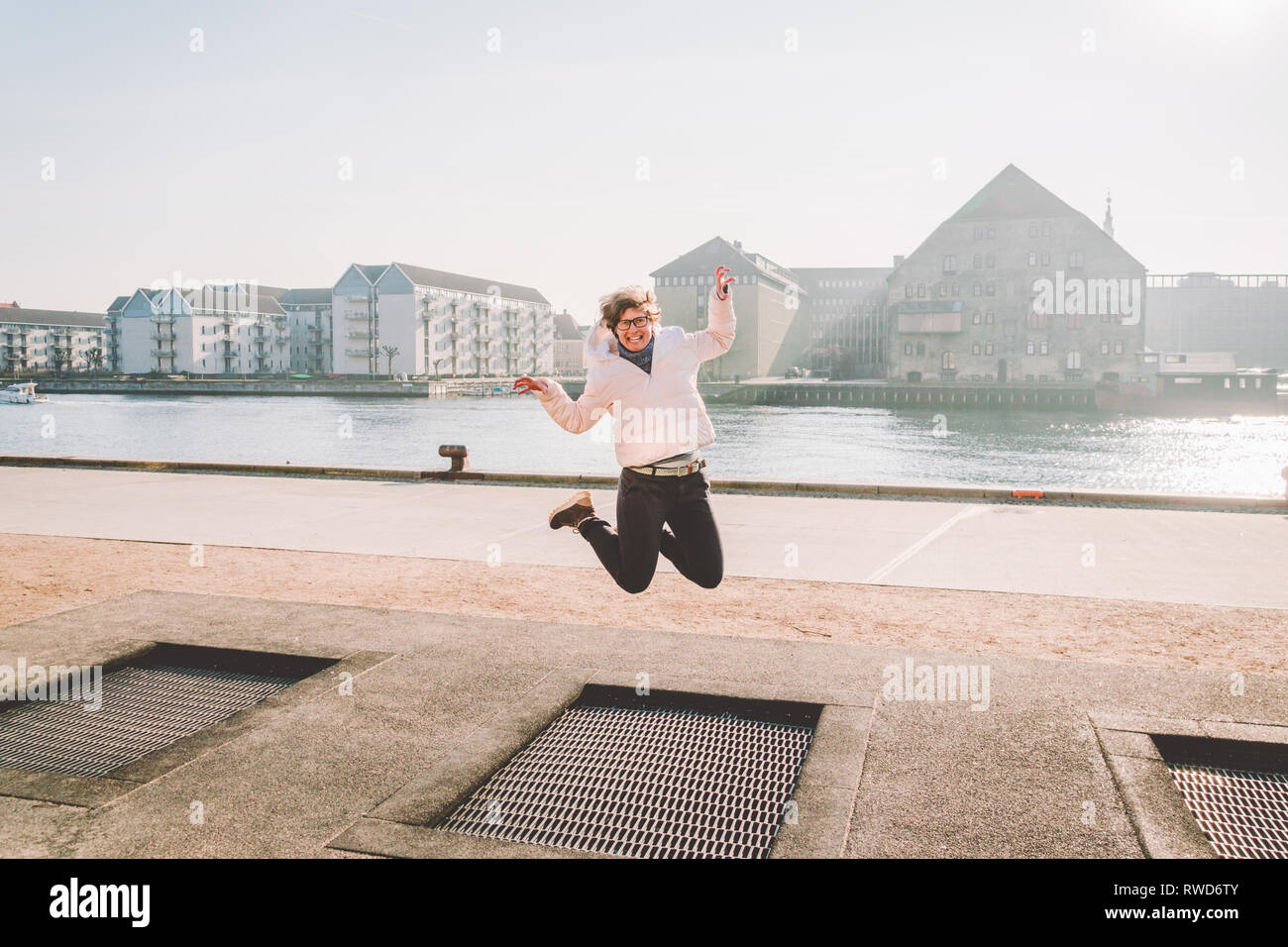 adult person rejoices like child. Playground trampoline in ground, children trampoline, springs throws people up fun and cool. Copenhagen River Embank Stock Photo