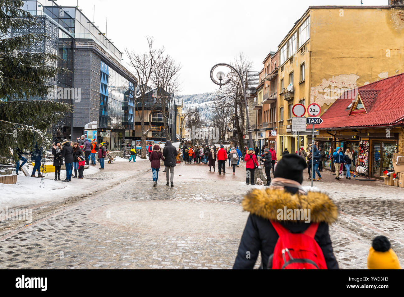 Zakopane, Poland - February 22, 2019. A crowd of people is walking along Krupowki street on an winter day. Krupowki street is the main city promenade Stock Photo