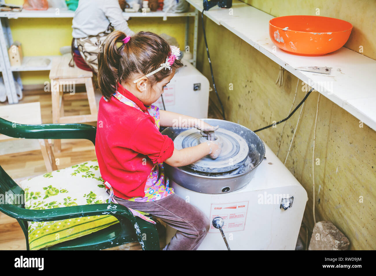 little girl learning shaping clay on pottery wheel at arts workshop ...