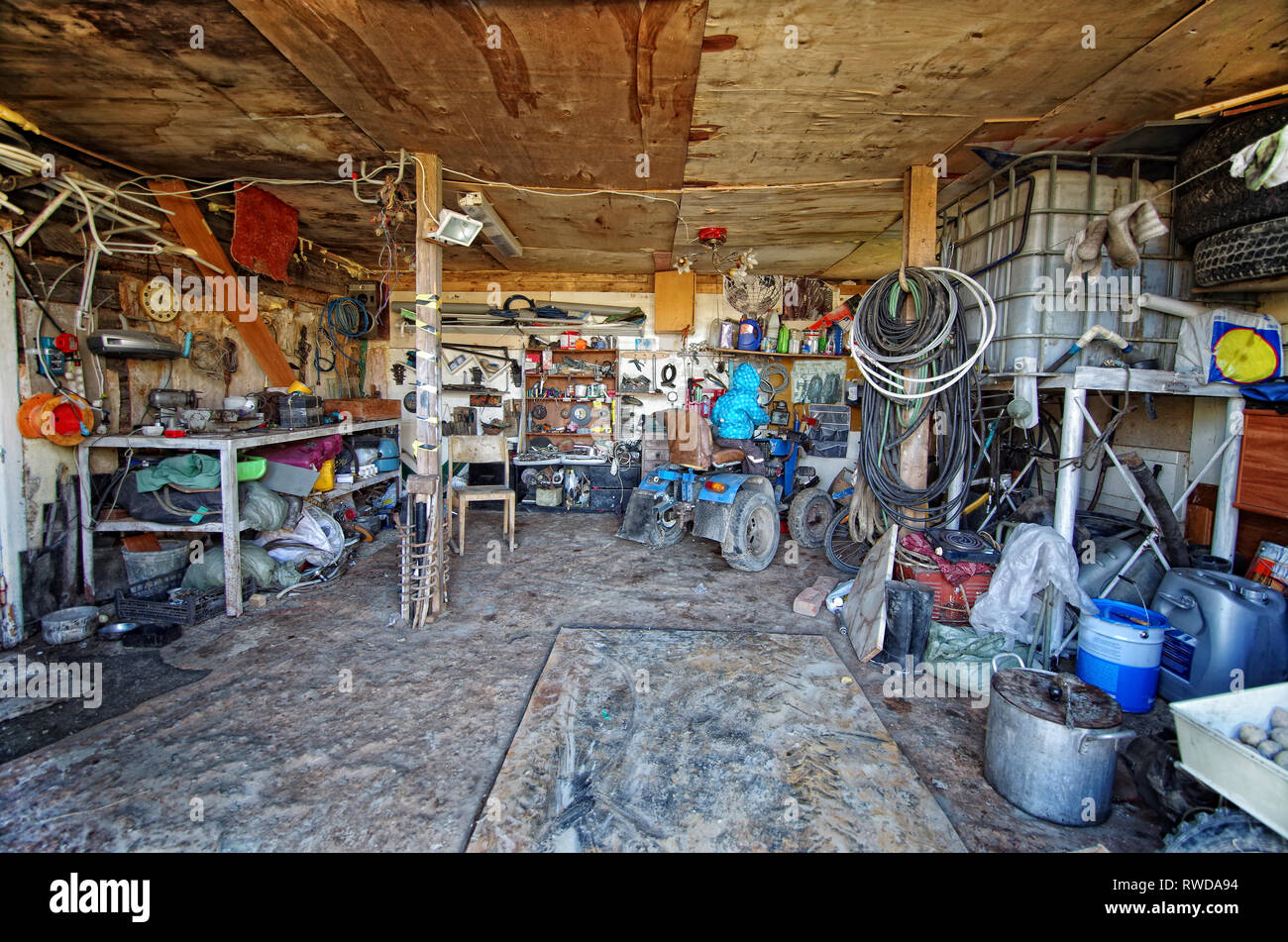 Inside a messy and cluttered garage shed with tools, cans, garden equipment in organised chaos Stock Photo