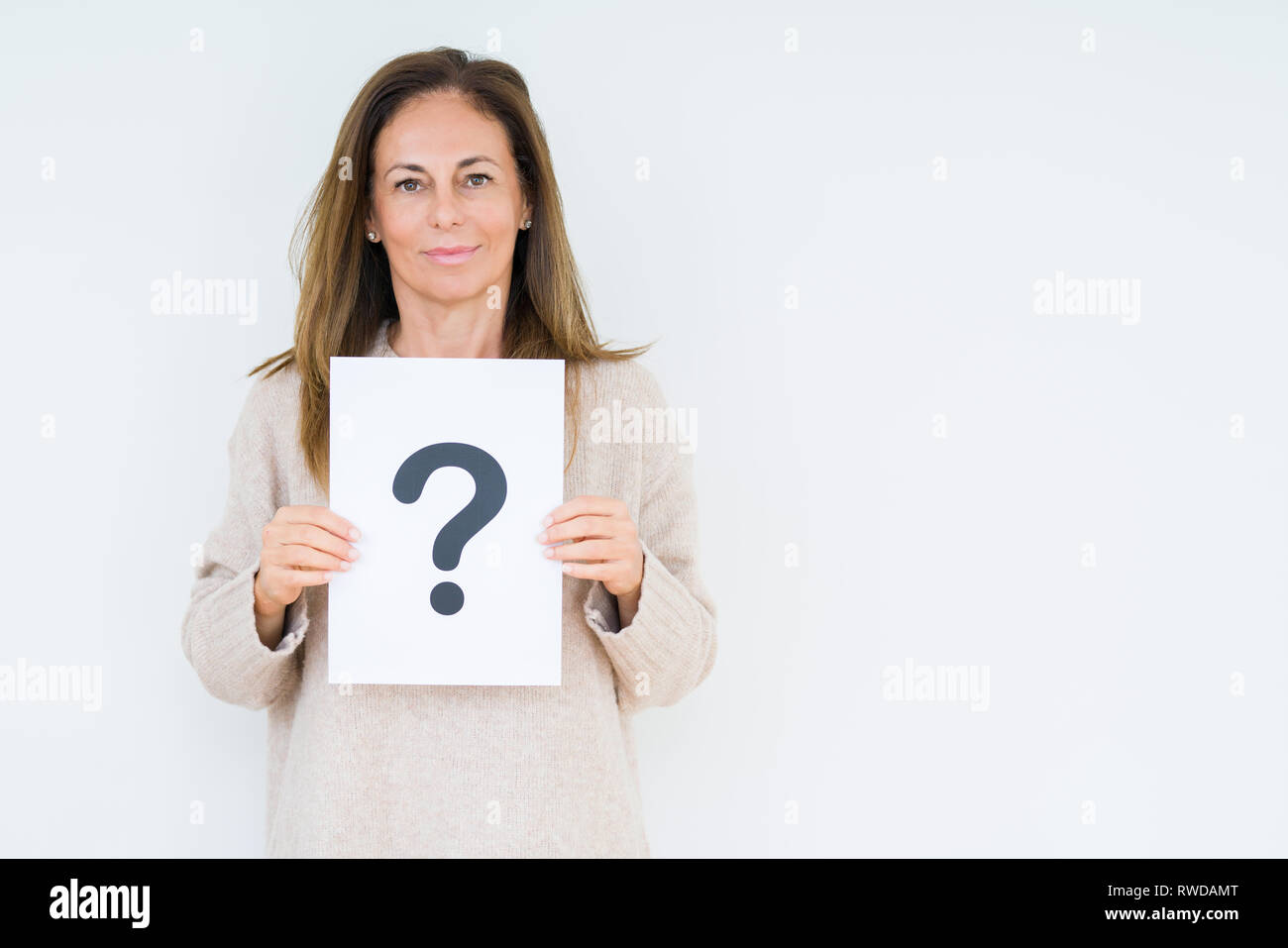 Middle age woman thinking and holding paper with question mark symbol ...