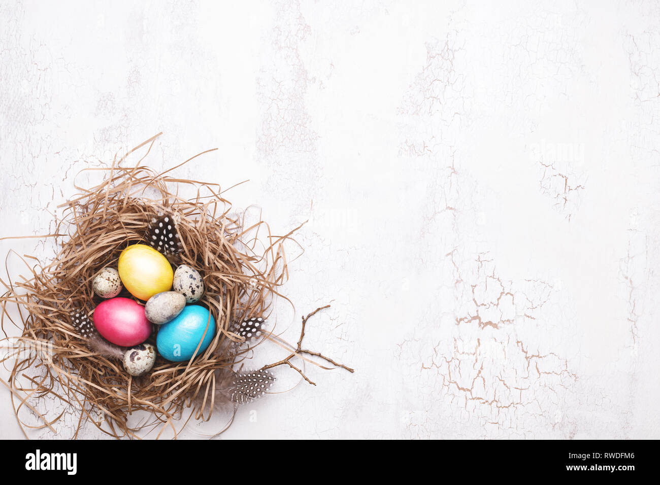 Colorful Easter eggs in nest on white craquelure background. Top view ...