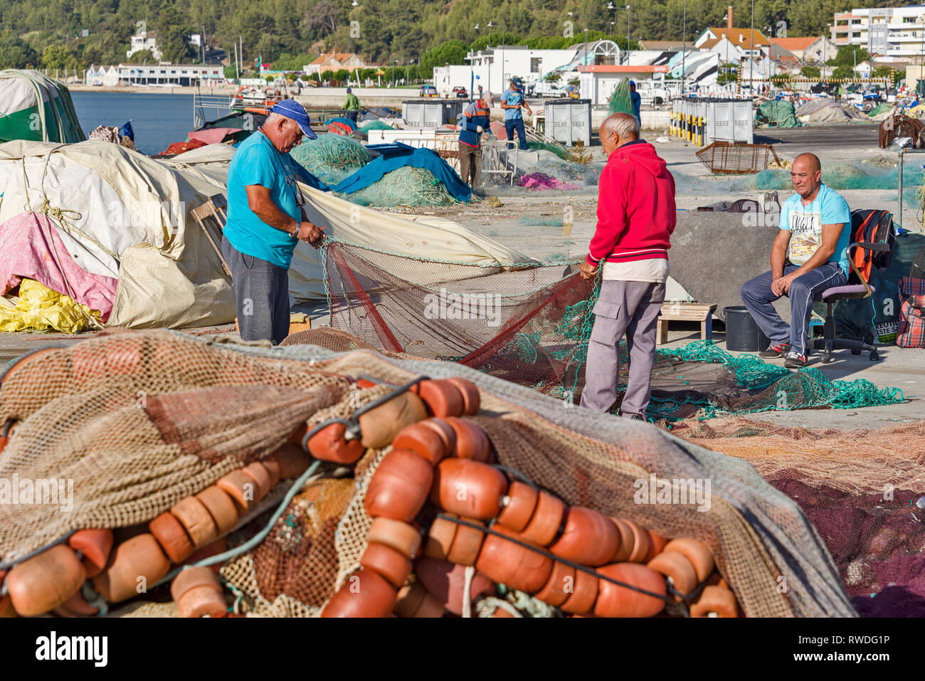fishermen repair their nets on a pier at the port of Setubal