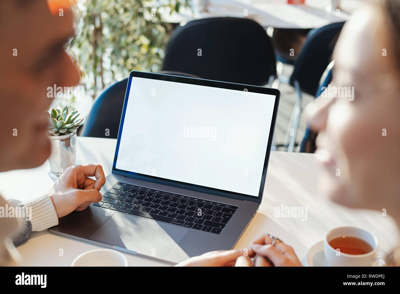 Young man and woman working in front of the laptop with blank white