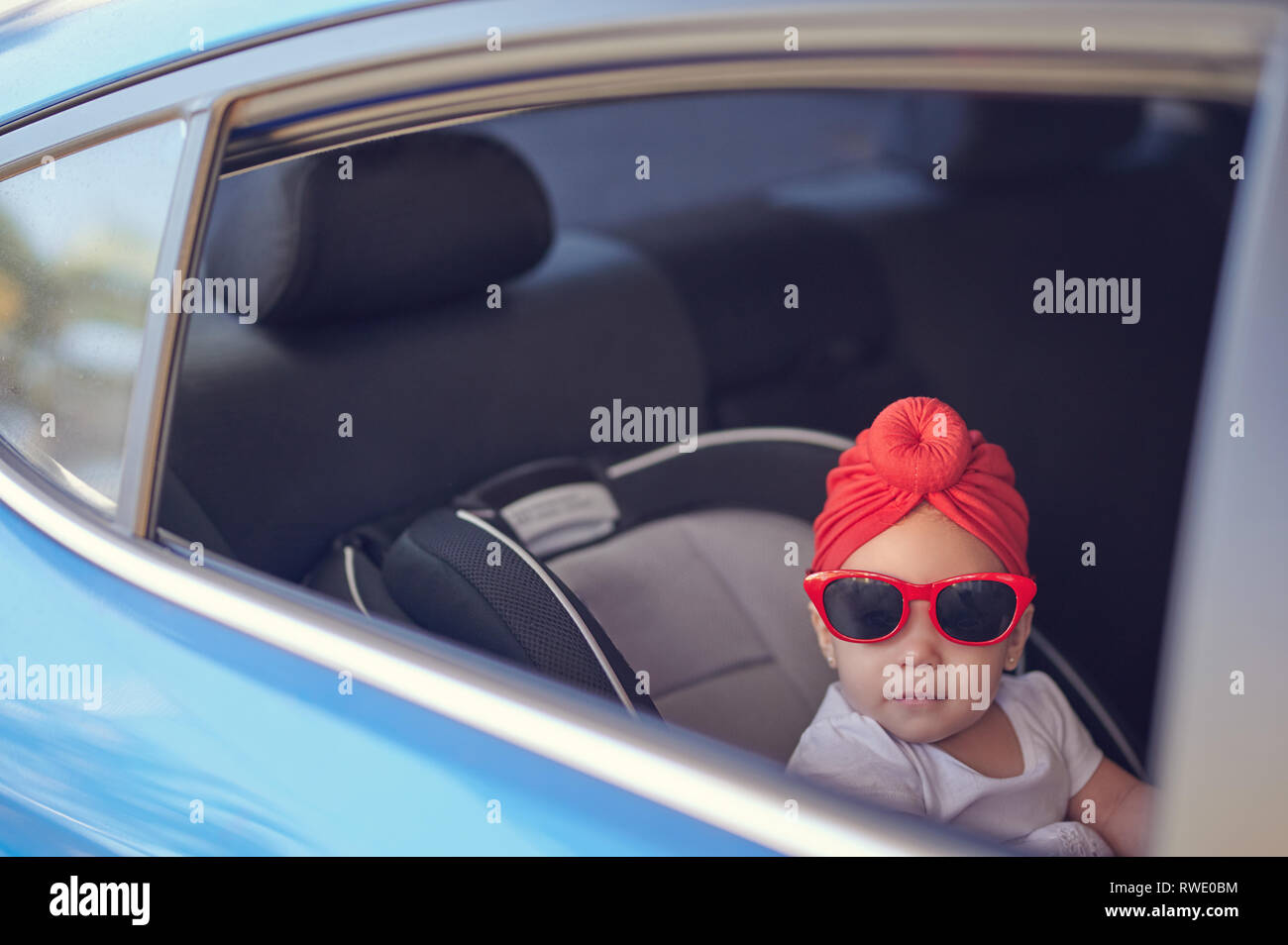 Baby in sunglasses in car seat looking to camera Stock Photo