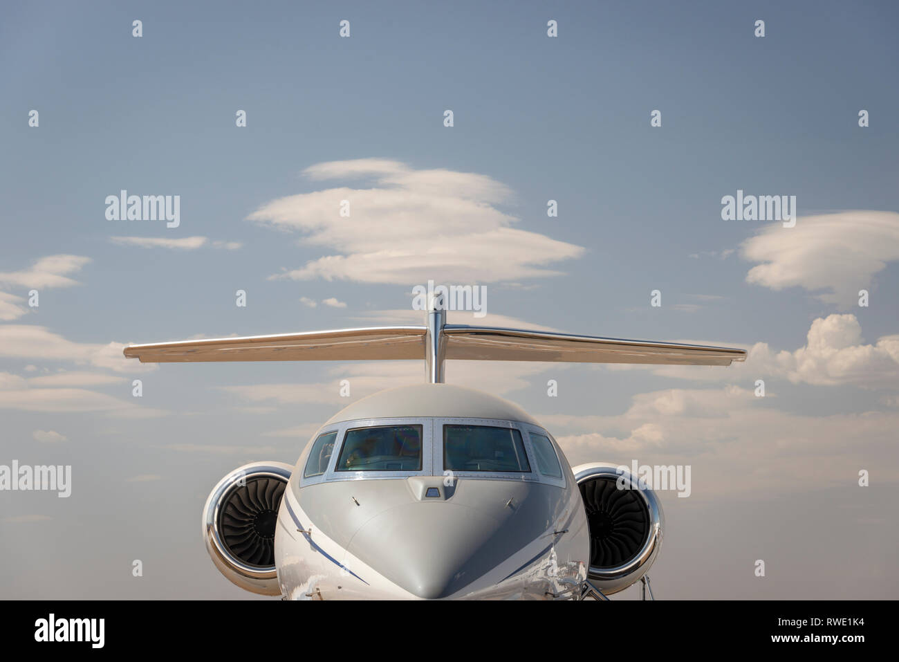A personal luxury jet aircraft against a blue sky with cloud Stock Photo